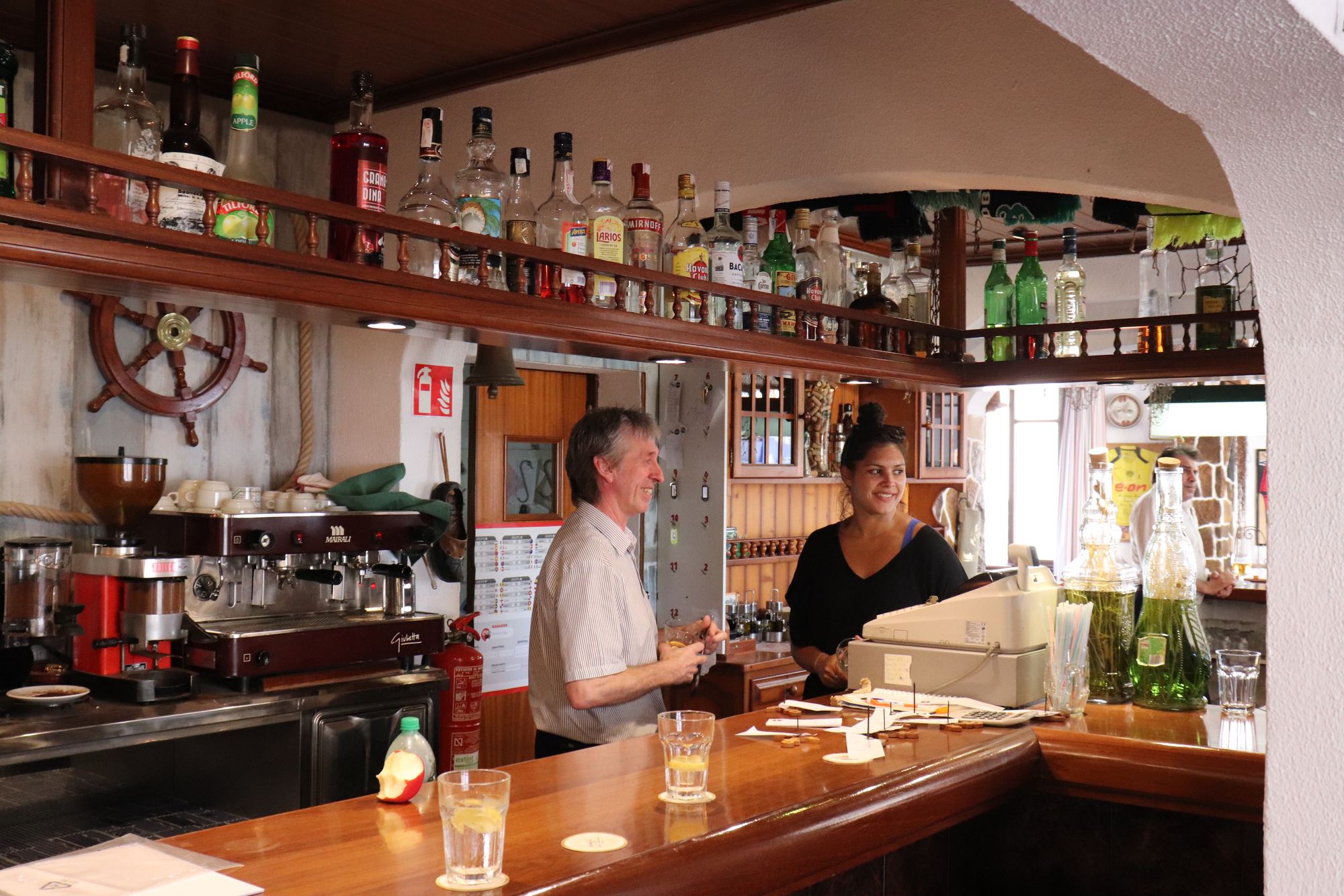 The hostal's sports bar in warm wood, bottles ranged along the back wall, a wide counter and the family at work behind it