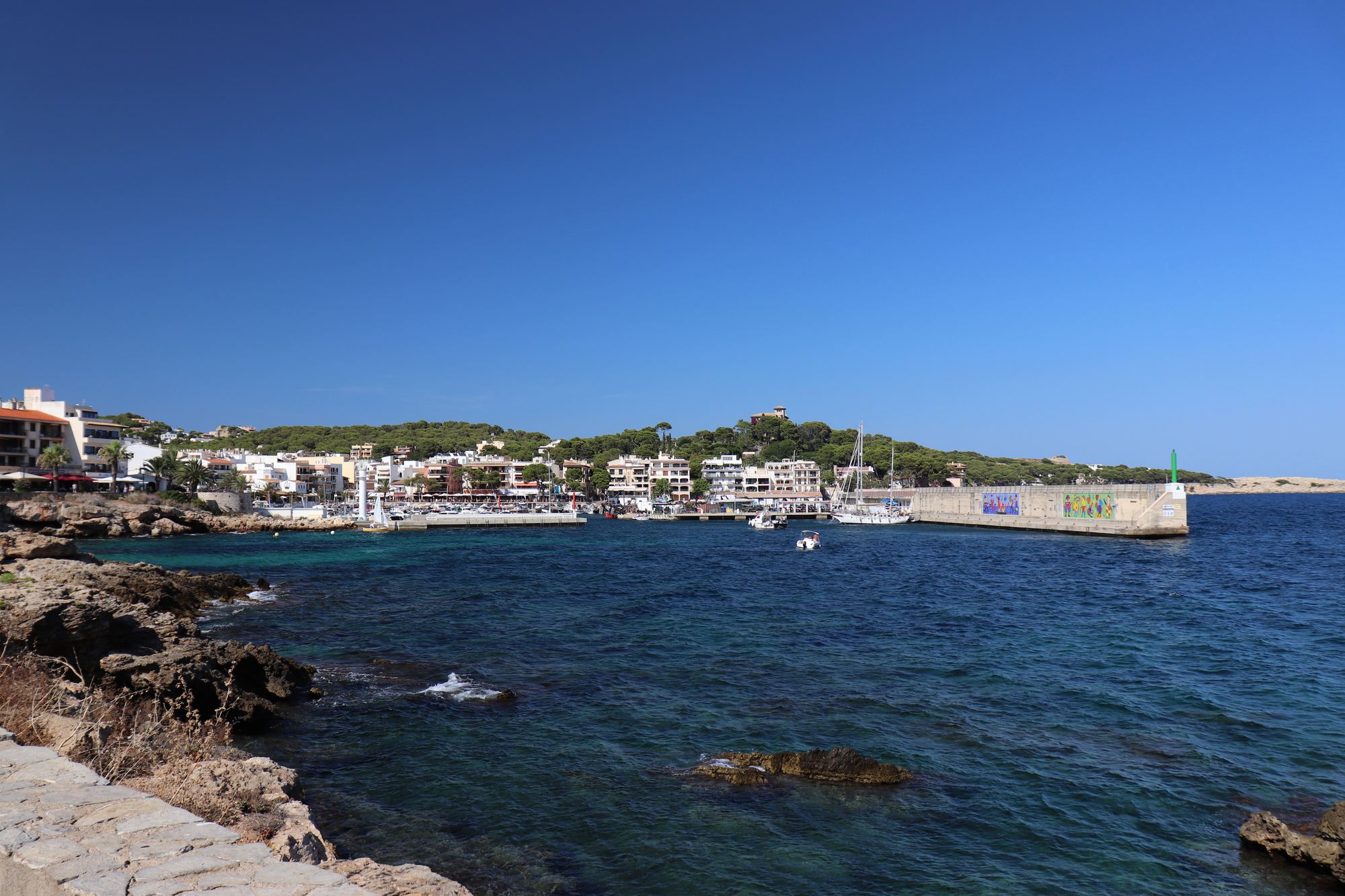 The path along the rocks above the sea at Cala Ratjada, the bay and moored boats in the distance