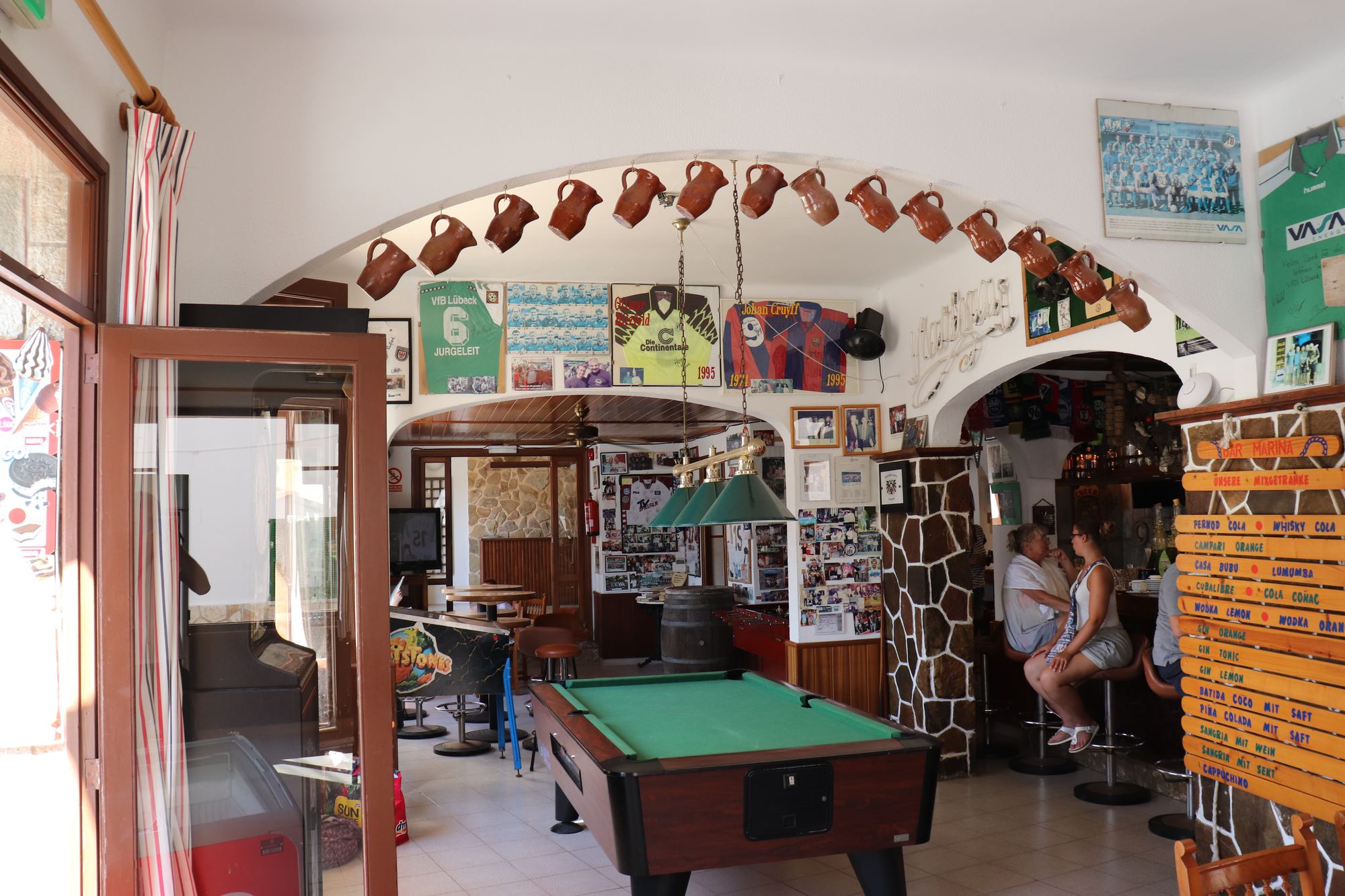 The arched entrance hall of the hostal, painted bright, hung with nautical odds and ends and a noticeboard of local trips