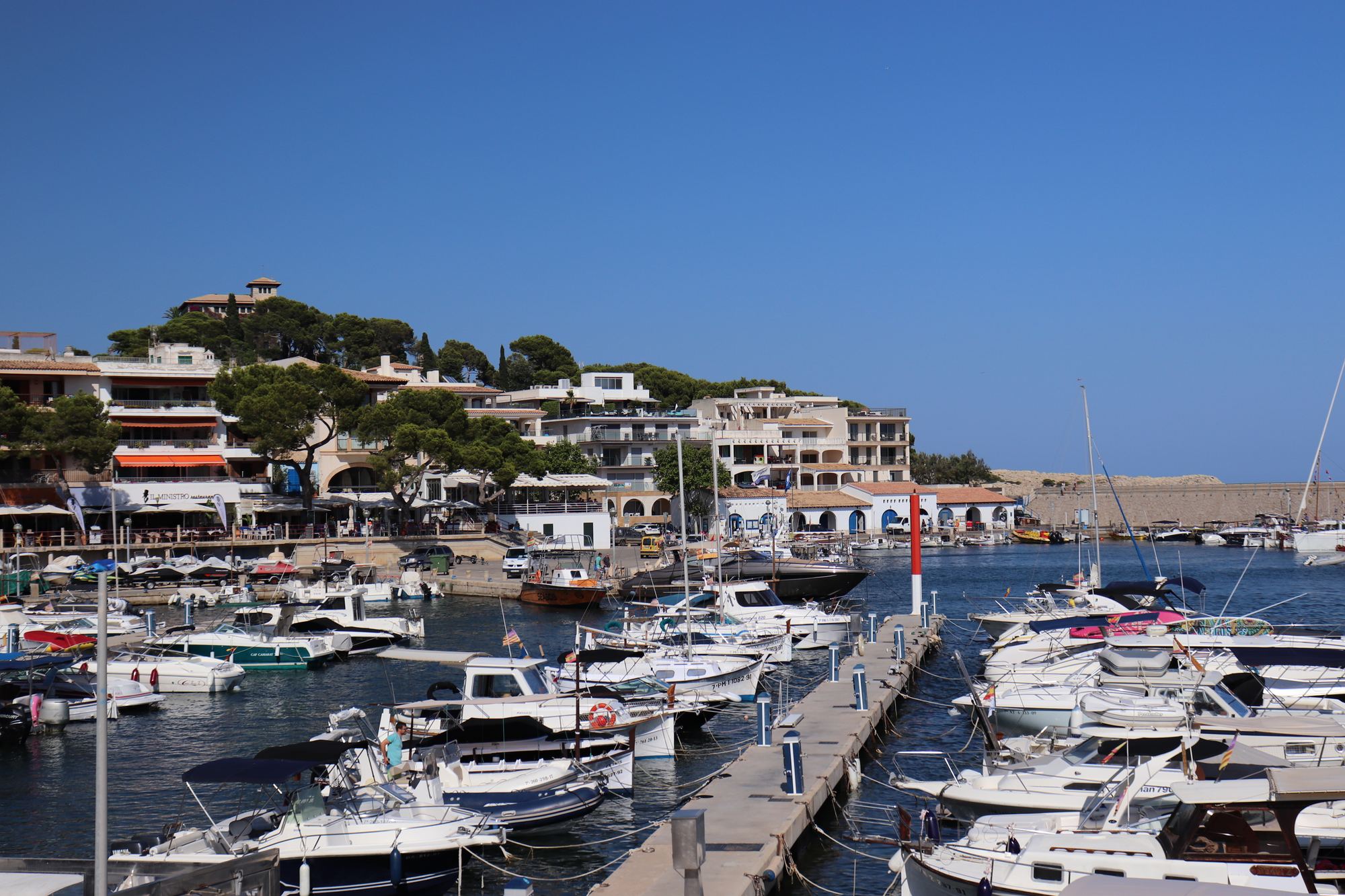 The harbour at Cala Ratjada: white boats moored in turquoise water, the town climbing the green hillside behind